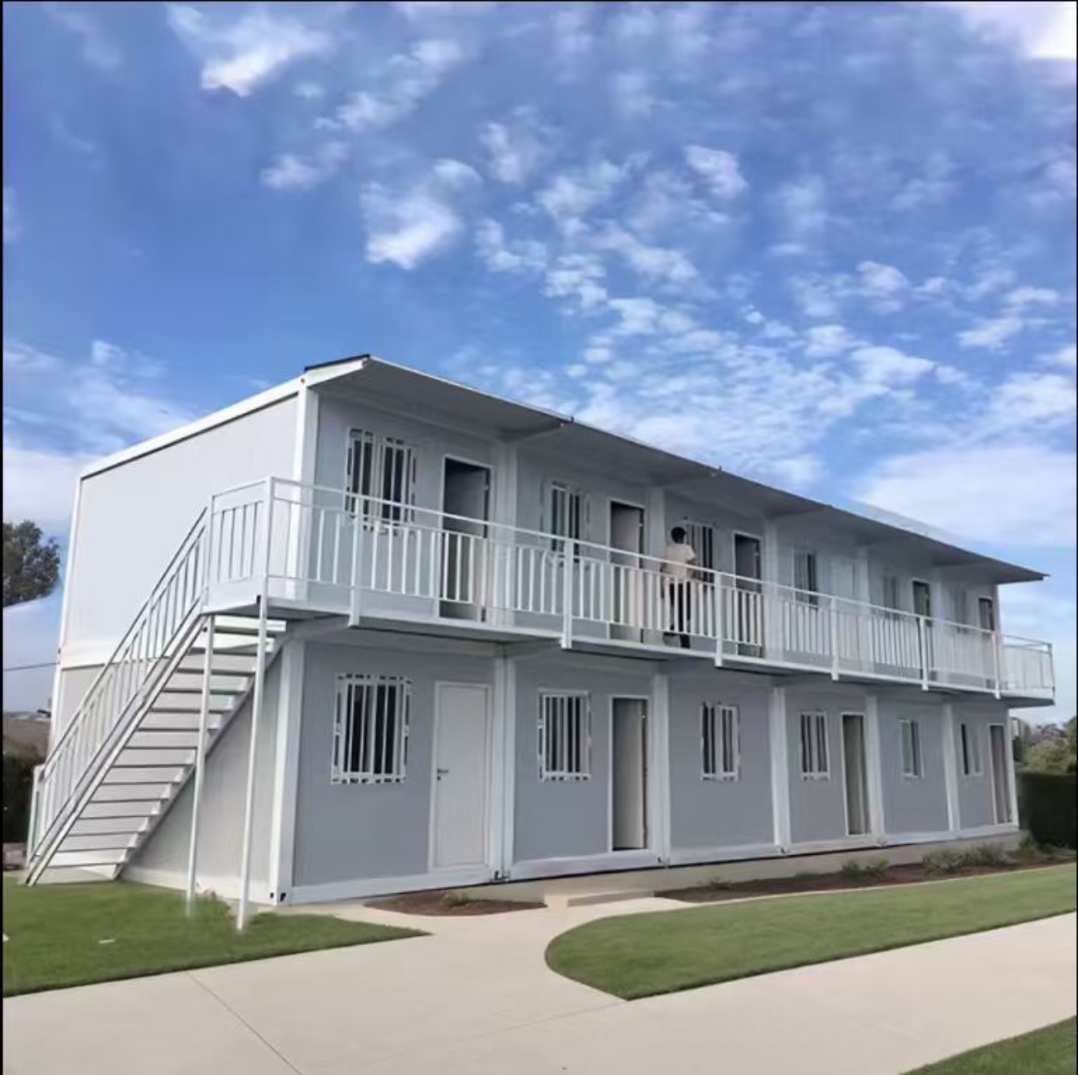תצורה דו קומתית של מבנה מודולרי לבן עם מדרגות ומרפסת חיצונית